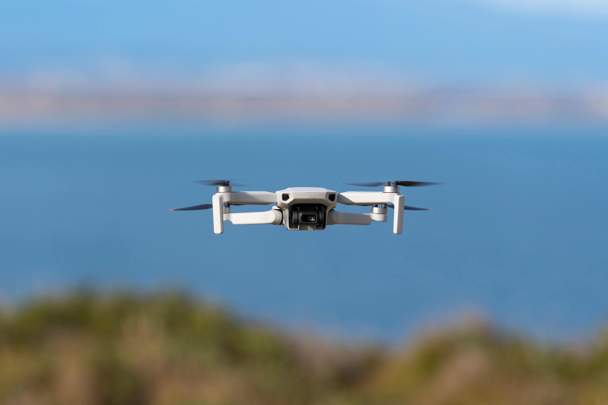 Small drone flying still with a defocused sea background